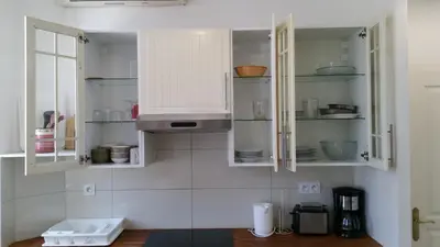 a kitchen with white cupboards with dishes in it at Palais Rialto in Nice