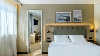 a bedroom with a large bed and a mirror at Campanile PRIME - Nice Airport in Nice