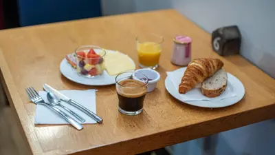 a table with two plates of food and two glasses of juice at Campanile PRIME - Nice Airport in Nice