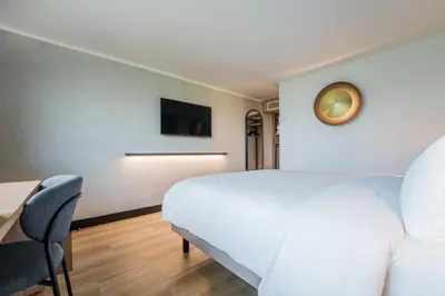 a bedroom with a bed and a desk and a tv at Campanile PRIME - Nice Airport in Nice
