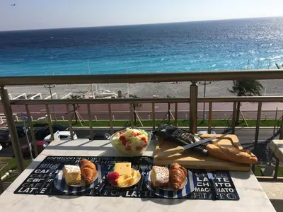 a table with food on a balcony with a view of the ocean at LE MIRAGE, SEA FRONT view, 3 bedrooms, 100m in Nice