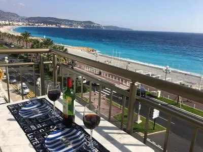 a table with wine glasses and a view of the beach at LE MIRAGE, SEA FRONT view, 3 bedrooms, 100m in Nice