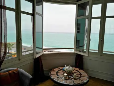 a room with a table and a view of the ocean at LE MIRAGE, SEA FRONT view, 3 bedrooms, 100m in Nice