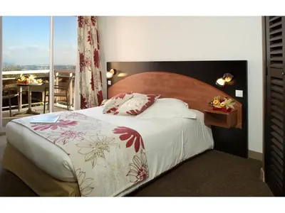 a bedroom with a large bed with a large window at Hôtel Du Baou in La Gaude