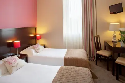 a hotel room with two beds and a desk at Hôtel Relais Acropolis in Nice