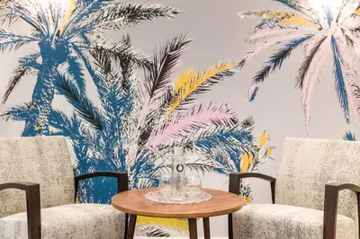 a room with two chairs and a table with palm trees mural at Palais Saleya Boutique Hôtel in Nice