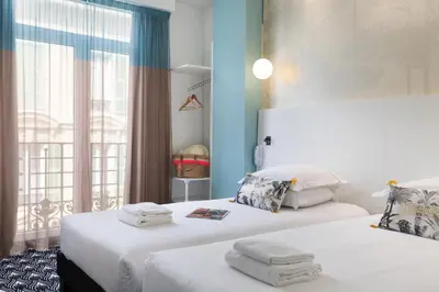 two white beds in a room with a window at Hôtel Byakko Nice in Nice