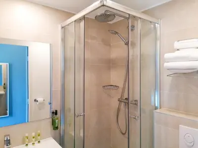 a shower with a glass door in a bathroom at Hôtel Du Centre, un hôtel AMMI in Nice