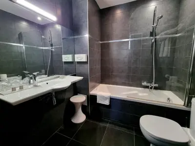 a bathroom with a tub and a sink and a toilet at Hotel Carlton Nice in Nice