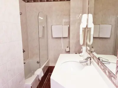 a white bathroom with a sink and a shower at Hotel Carlton Nice in Nice
