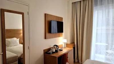 a hotel room with a bed and a television on a wall at Hotel Carlton Nice in Nice
