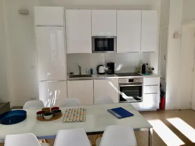 a kitchen with white cabinets and a table and chairs at Apartment on Place Massena in Nice