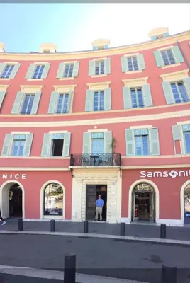 a man standing in the doorway of a red building at Apartment on Place Massena in Nice