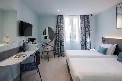 a hotel room with two beds and a desk at Best Western Alba in Nice
