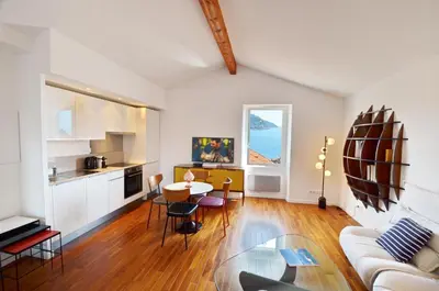 a living room with a table and a kitchen at Villefranche Sur Mer One Bed in Villefranche-sur-Mer