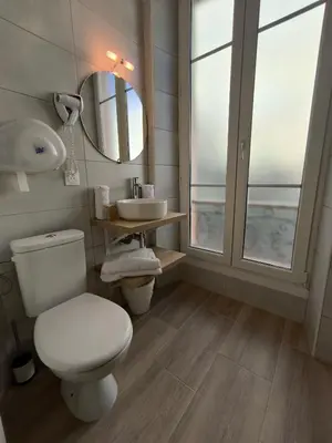 a bathroom with a toilet and a sink and a mirror at Hôtel Amaryllis in Nice