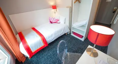 a bedroom with a white bed with a pink bow on it at Hôtel Amaryllis in Nice