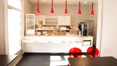 a kitchen with red pendant lights above a counter at Hôtel Amaryllis in Nice