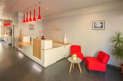 a waiting room with red chairs and a counter at Hôtel Amaryllis in Nice