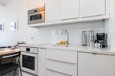 a white kitchen with white cabinets and a table at Sea view - 2 Bdr Promenade des Anglais in Nice