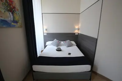 a small bedroom with a bed with white sheets at Boutique Hôtel Neptune Nice in Nice