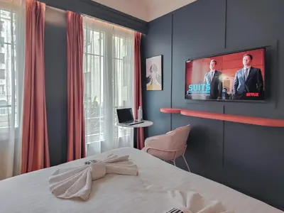a bedroom with a bed and a tv on the wall at Hotel Aparthotel AMMI Nice Lafayette in Nice