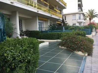 a building with plants and a sidewalk in front of it at Beachfront apartment Promenade Des Anglais in Nice