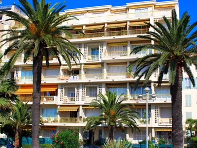 a hotel with palm trees in front of it at Beachfront apartment Promenade Des Anglais in Nice
