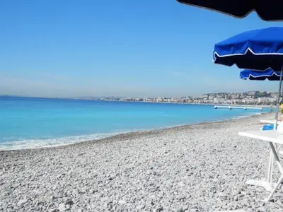 a beach with a table and an umbrella and the ocean at Appartement carre d'or in Nice