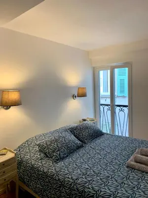 a bedroom with a bed and two lamps and a window at Rue Neuve - Old Town Apartment in Nice