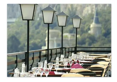 a row of tables with wine glasses on a balcony at Hôtel Le Versailles in Villefranche-sur-Mer