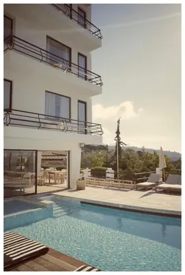 a house with a swimming pool next to a building at Hôtel Le Versailles in Villefranche-sur-Mer