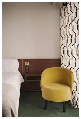 a yellow chair in a bedroom next to a bed at Hôtel Le Versailles in Villefranche-sur-Mer