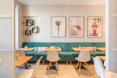 a restaurant with a green couch and tables and chairs at Hotel Select in Beaulieu-sur-Mer