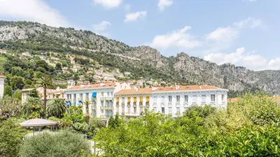 a group of buildings in front of a mountain at Hotel Select in Beaulieu-sur-Mer