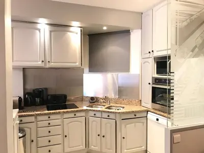 a white kitchen with white cabinets and a sink at Palais Haydee in Nice