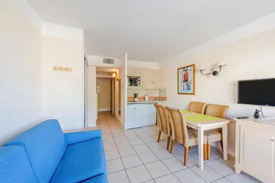 a living room with a blue couch and a table and chairs at Residence Heliotel Marine - maeva Home in Saint-Laurent-du-Var