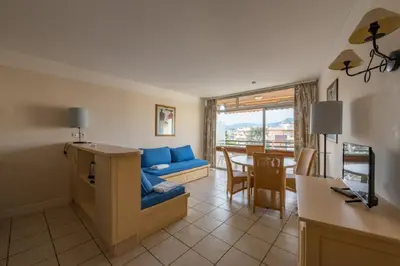 a living room with a blue couch and a table at Residence Heliotel Marine - maeva Home in Saint-Laurent-du-Var