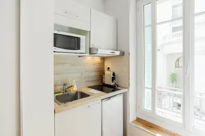 a kitchen with white cabinets and a sink and a window at Nice Home - Studios Lido in Nice