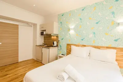 a bedroom with a white bed with a blue wall at Nice Home - Studios Lido in Nice