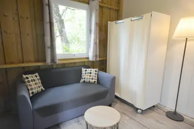 a living room with a blue couch and a window at Camping Les Cent Chênes in Saint-Jeannet