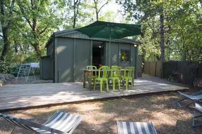 a green tiny house with chairs on a deck at Camping Les Cent Chênes in Saint-Jeannet