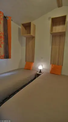 a room with two beds and a lamp on a table at Camping Les Cent Chênes in Saint-Jeannet
