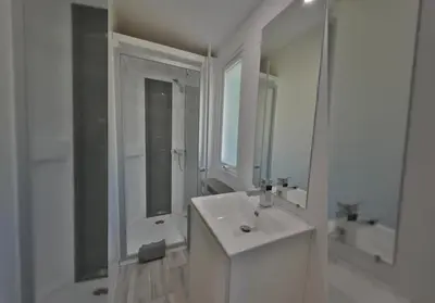 a white bathroom with a sink and a mirror at Camping Les Cent Chênes in Saint-Jeannet