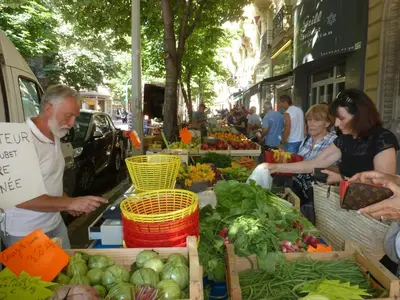 a group of people standing around a market with vegetables at beau studio in Nice