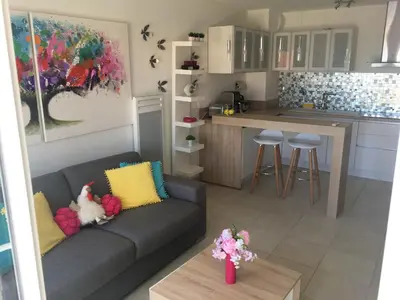 a living room with a couch and a kitchen at Riviera Terrasse - parking gratuit in Nice