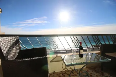 a glass table with a bottle of wine on a balcony at Promenade des anglais Vue mer in Nice