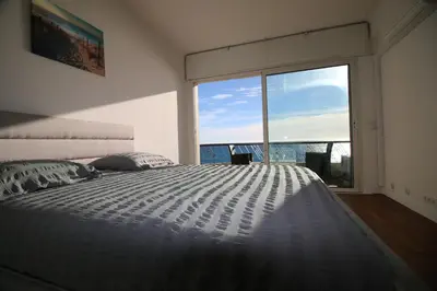 a bedroom with a large bed and a large window at Promenade des anglais Vue mer in Nice