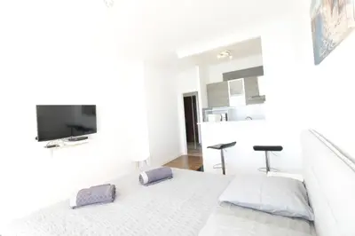 a white bedroom with a bed and a couch at Promenade des anglais Vue mer in Nice