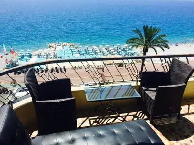 a balcony with chairs and a table and a beach at Promenade des anglais Vue mer in Nice